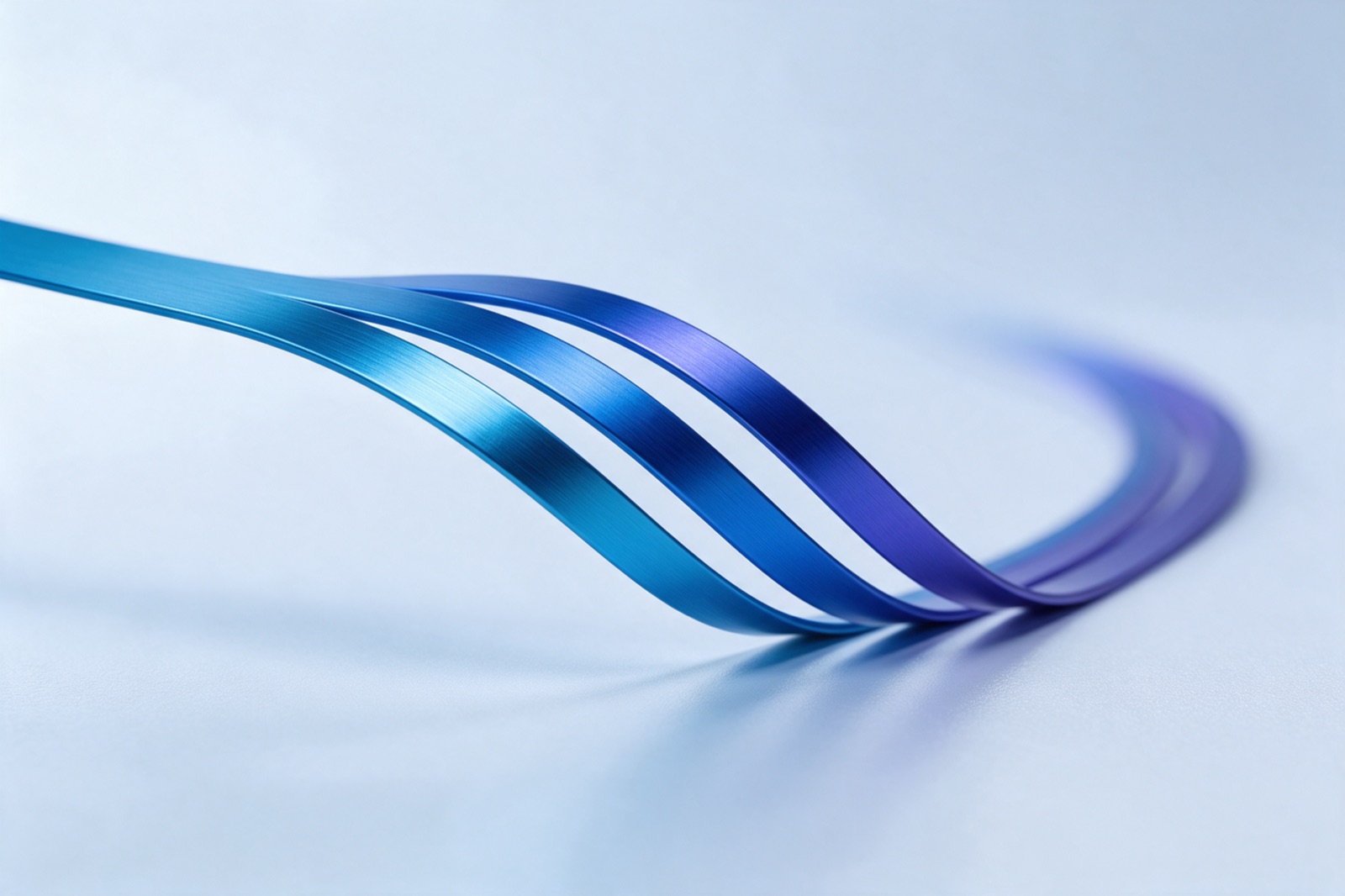 A single anodised aluminium ribbon dividing into three parallel routes that curve away across a white surface.